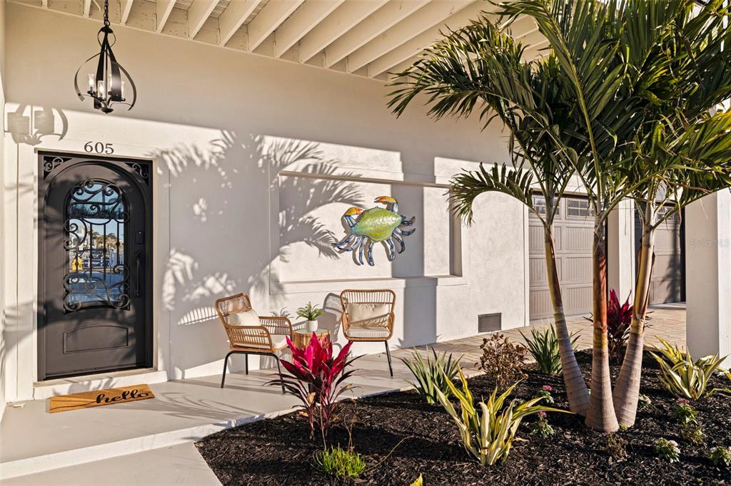 A front entryway features a black door, two wicker chairs, and a decorative crab wall hanging — 605 115TH AVENUE, TREASURE ISLAND, FL