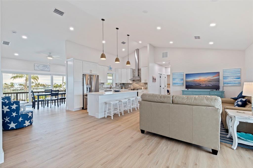An open-concept kitchen and living area features white cabinetry, a central island, and light flooring — 605 115TH AVENUE, TREASURE ISLAND, FL