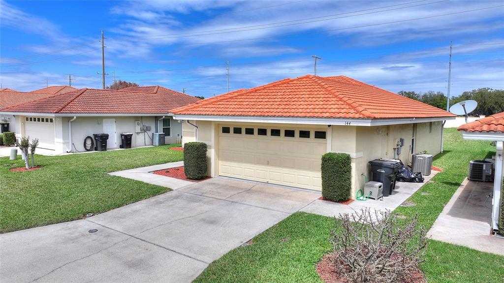 A beige single-story house with a red tile roof and a two-car garage — 144 MORNING GLORY CIRCLE, WINTER HAVEN, FL