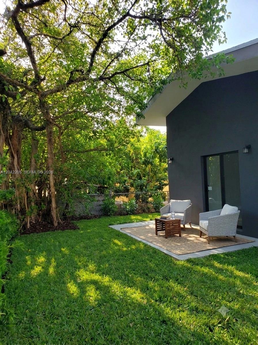 A gray house exterior features a patio with two wicker chairs and a small table — 313 NE 169th St, North Miami Beach FL 33162, NORTH MIAMI BEACH, FL