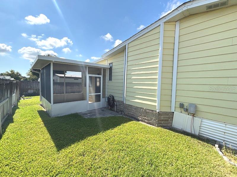 A yellow house with a screened-in porch sits next to a wooden fence — 719 FIELDSTONE AVENUE, PORT ORANGE, FL