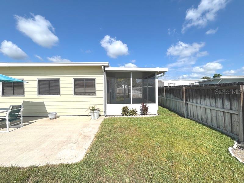 A light yellow house with a screened-in porch, concrete patio, and wooden privacy fence — 719 FIELDSTONE AVENUE, PORT ORANGE, FL