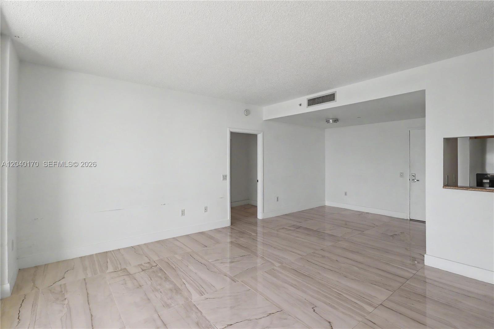 An empty room features white walls, a textured ceiling, and light-colored marble-patterned tile flooring — 2475 Brickell Ave # 704, Miami FL 33129, MIAMI, FL