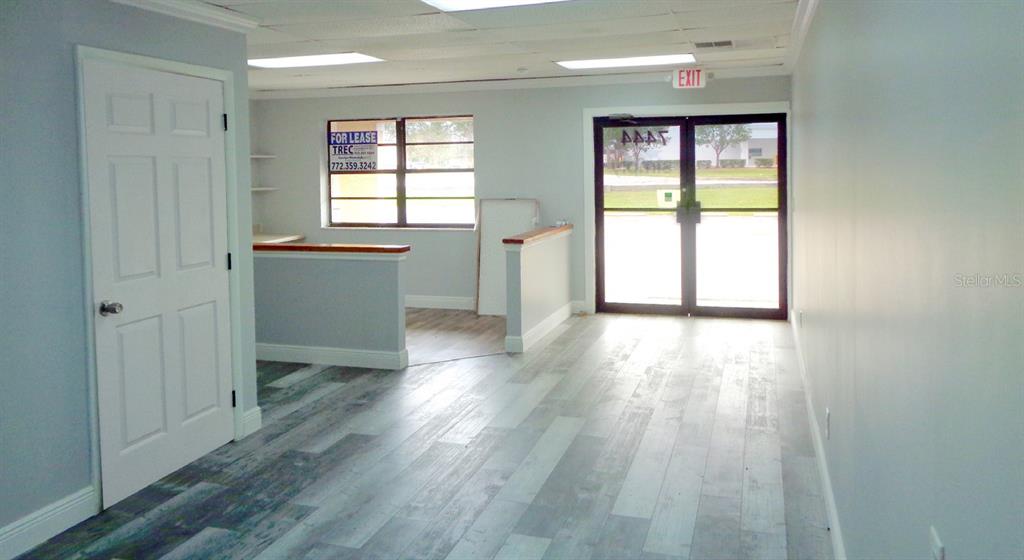 An interior view of a commercial space featuring light wood-look flooring and a reception counter — 7444 S FEDERAL HWY HIGHWAY, PORT ST LUCIE, FL