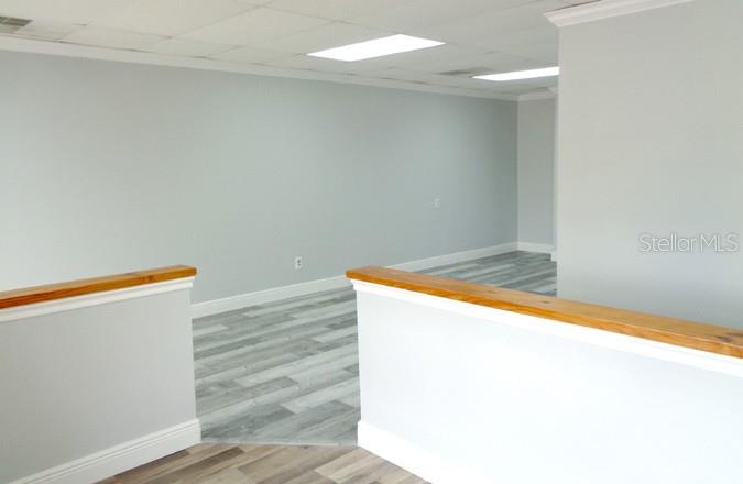 An interior view shows a room with light gray walls, wood-look flooring, and wooden railings — 7444 S FEDERAL HWY HIGHWAY, PORT ST LUCIE, FL