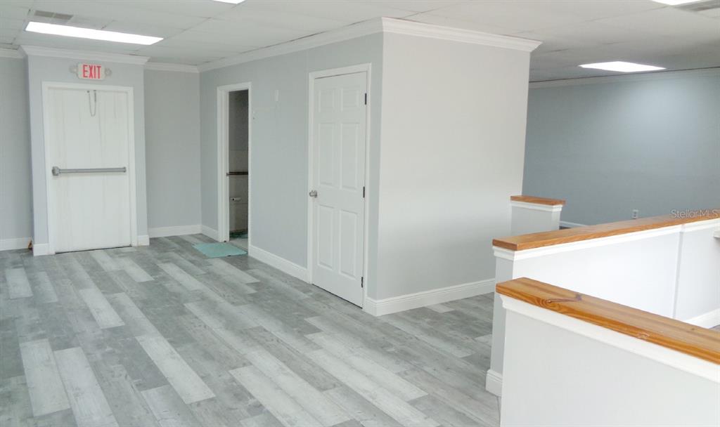An interior view shows a room with gray wood-look flooring, white walls, and three doors — 7444 S FEDERAL HWY HIGHWAY, PORT ST LUCIE, FL