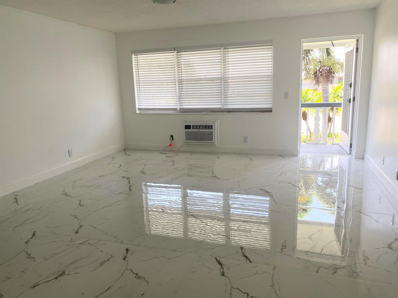 An empty room with white walls, marble-look tile flooring, a window air conditioner, and balcony access — 341 Windsor O, West Palm Beach FL 33417, WEST PALM BEACH, FL