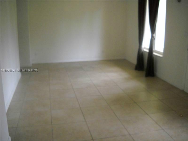 An empty room features light-colored floor tiles, white walls, and a window with dark curtains — 1040 92 ST # 3, Bay Harbor Islands FL 33154, BAY HARBOR ISLANDS, FL