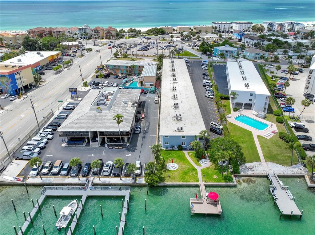 An aerial view shows two buildings with parking lots, a swimming pool, and a boat dock — 9715 HARRELL AVENUE UNIT 39, TREASURE ISLAND, FL