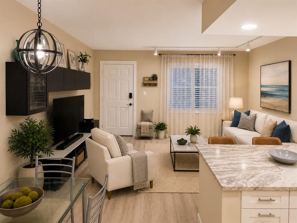 An open-concept living and dining area features a kitchen island, modern furniture, and light flooring — 9715 HARRELL AVENUE UNIT 39, TREASURE ISLAND, FL