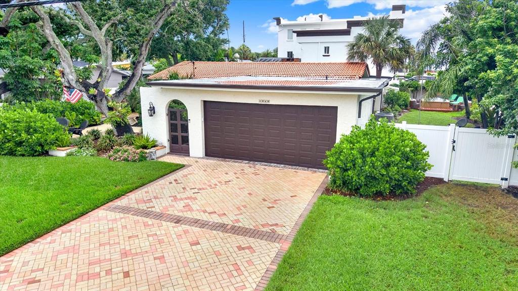 A detached garage with a brown door, arched side entrance, and a brick paver driveway — 1040 PALM DRIVE, BELLEAIR BEACH, FL