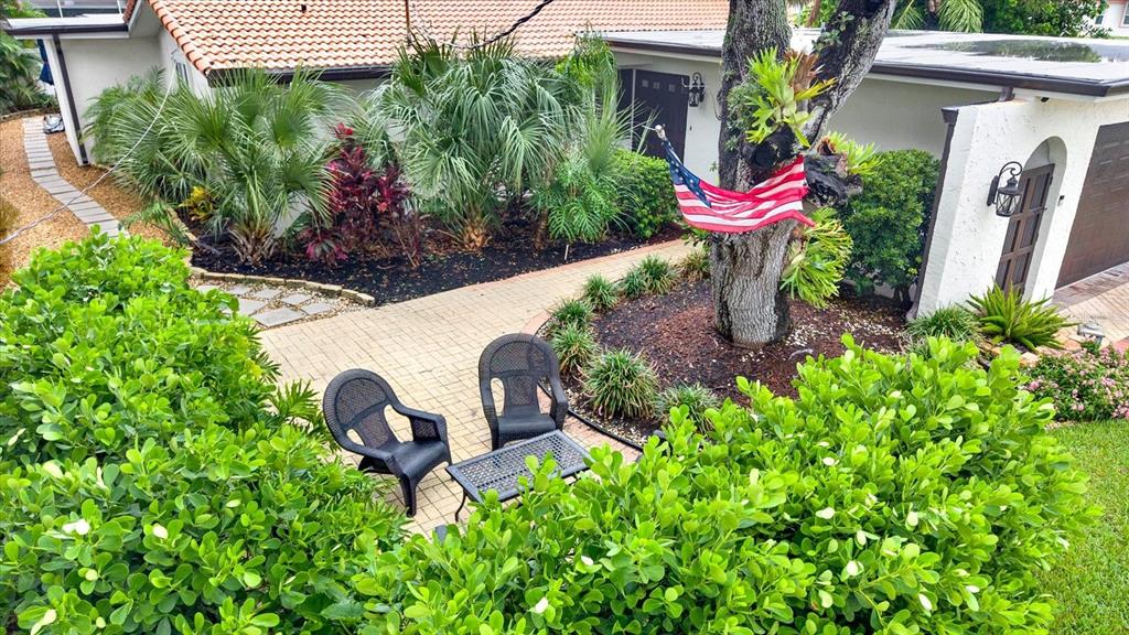 An elevated view of a paved patio with two chairs and a table near a tree — 1040 PALM DRIVE, BELLEAIR BEACH, FL