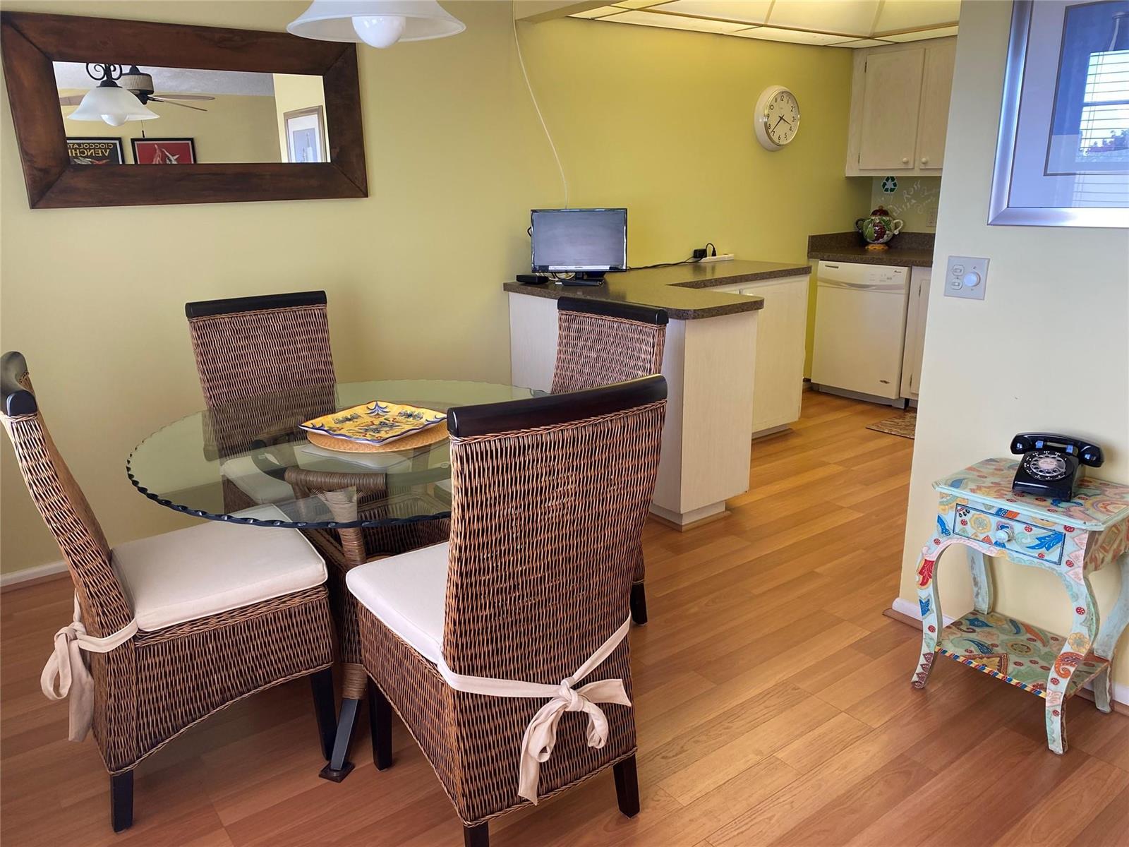 A dining area with a glass table, wicker chairs, and an adjacent kitchen with light flooring — 19 Ashby A # 19, Deerfield Beach FL 33442, DEERFIELD BEACH, FL
