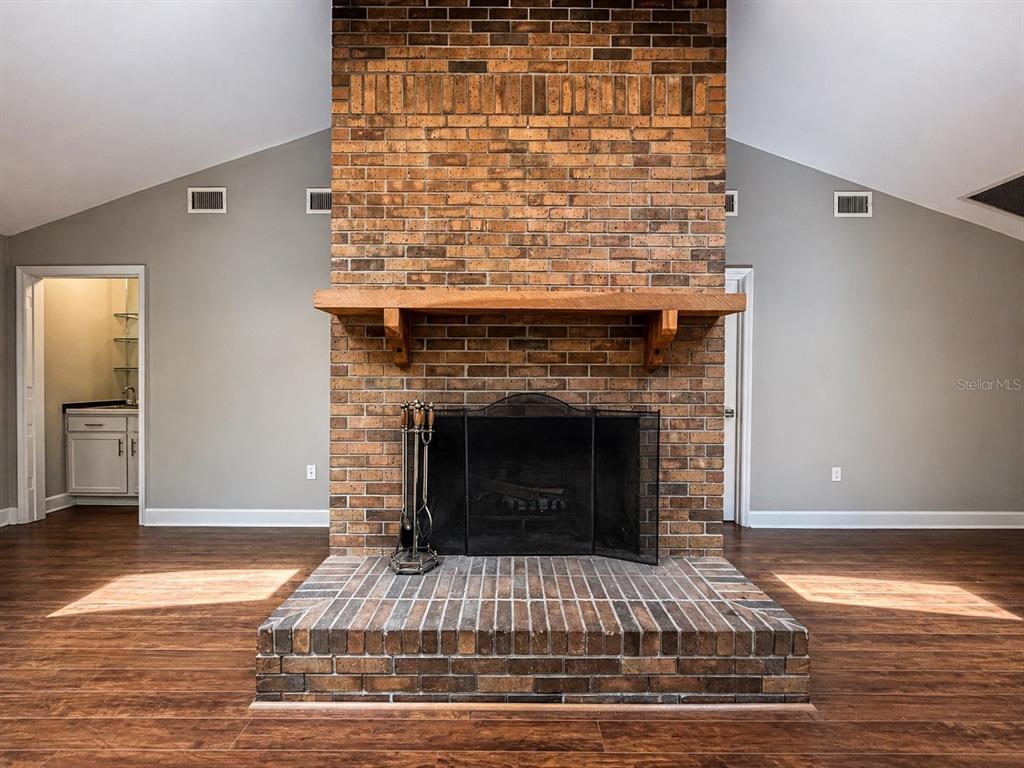A brick fireplace with a wooden mantel stands in a room with gray walls — 9331 NW 13TH PLACE, GAINESVILLE, FL