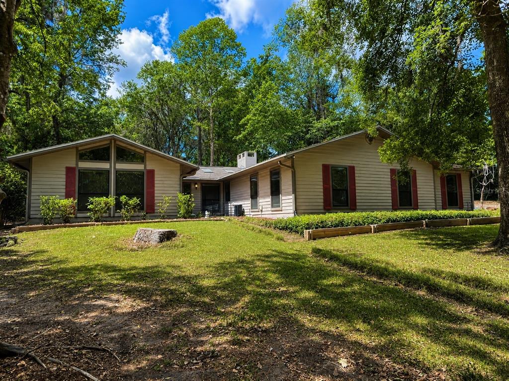 A single-story house with beige siding, red shutters, and a large front lawn — 9331 NW 13TH PLACE, GAINESVILLE, FL