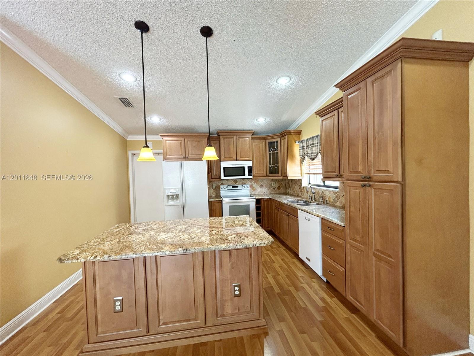 A kitchen features wood cabinets, granite countertops, a center island, and stainless steel appliances — 13931 SW 156th Ter, Miami FL 33177, MIAMI, FL