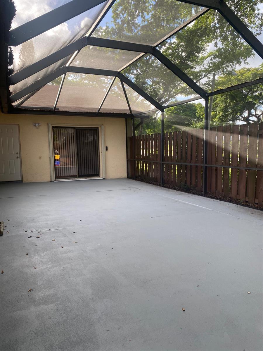 A screened-in patio with a concrete floor, sliding glass doors, and a wooden privacy fence — 1230 Summit Pl Circle Unit C, West Palm Beach FL 33415, WEST PALM BEACH, FL