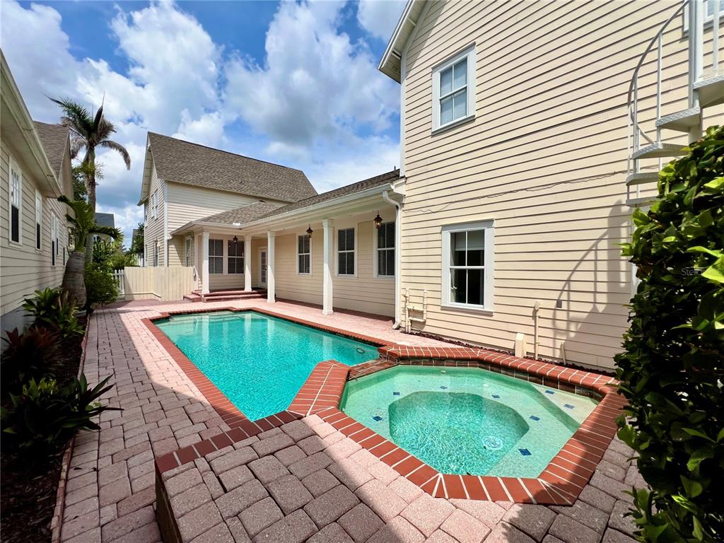 A backyard features a swimming pool and attached hot tub surrounded by brick pavers — 205 N VILLAGE STREET, CELEBRATION, FL