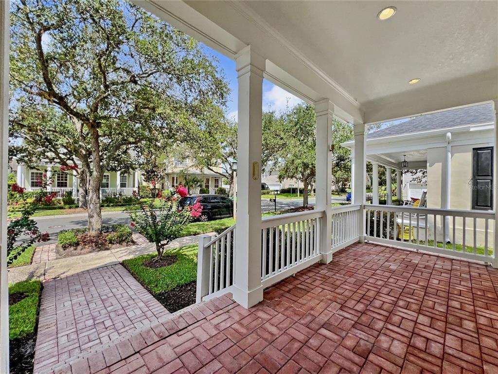A covered front porch features brick pavers, white railings, and square columns overlooking a neighborhood street — 205 N VILLAGE STREET, CELEBRATION, FL