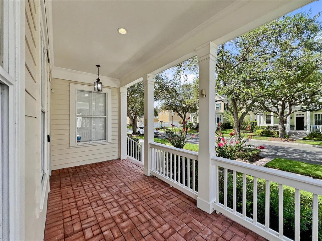 A covered front porch features a red brick floor, white railings, and light-colored siding — 205 N VILLAGE STREET, CELEBRATION, FL