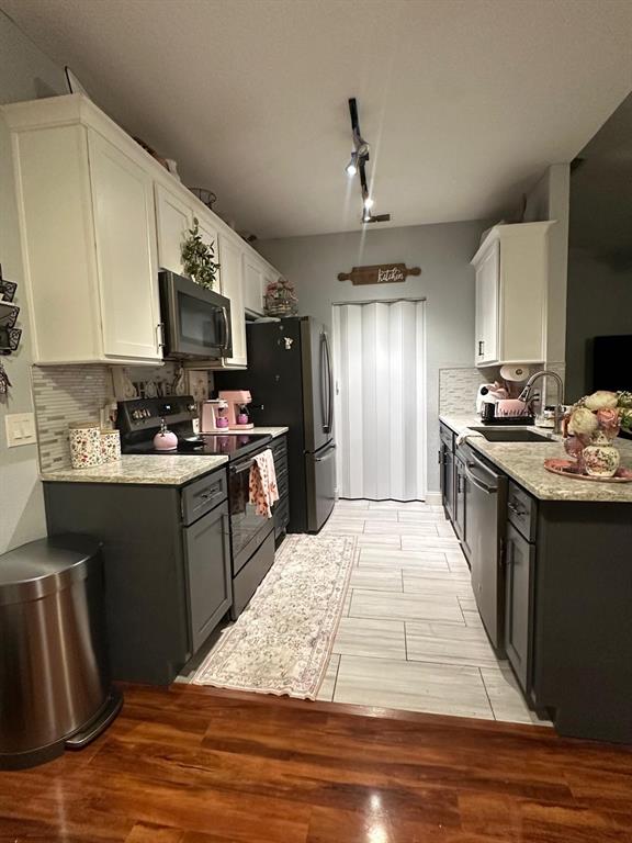 A kitchen features two-toned cabinetry, granite countertops, stainless steel appliances, and wood-look tile flooring — 875 GRAND REGENCY POINT UNIT 203, ALTAMONTE SPRINGS, FL