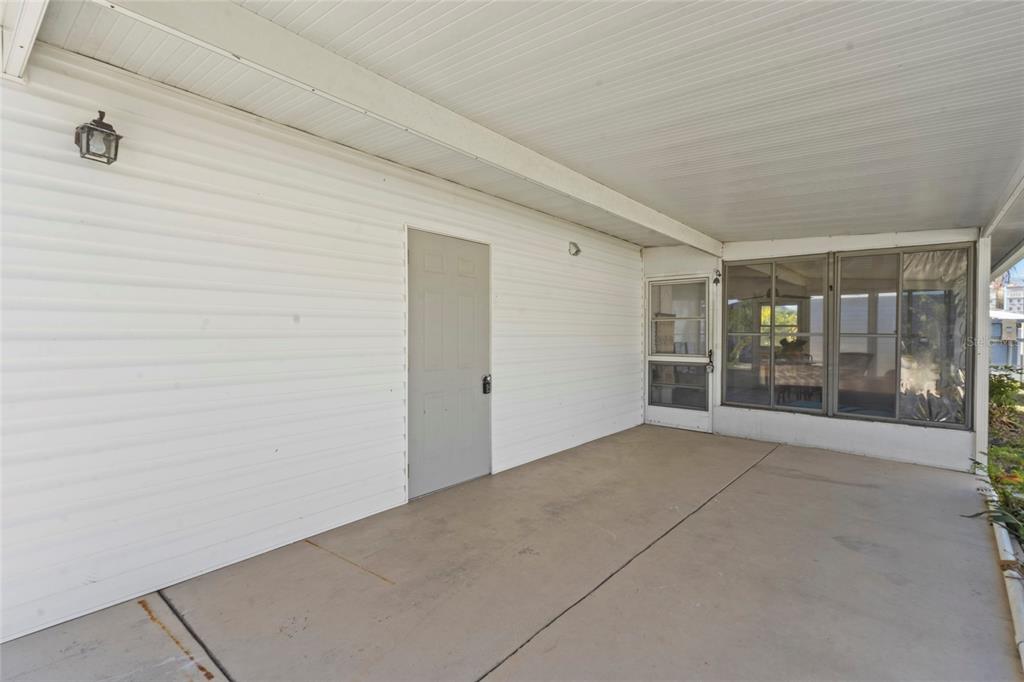 A covered concrete patio features white vinyl siding, a gray door, and a screened enclosure — 426 HATCHETT CREEK ROAD, VENICE, FL