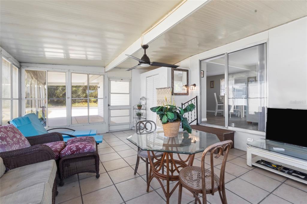 A sunroom features tile flooring, a glass-top dining table, wicker chairs, and sliding glass doors — 426 HATCHETT CREEK ROAD, VENICE, FL