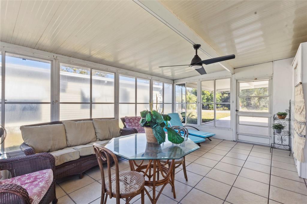 A sunroom with tile flooring, a glass-topped table, wicker furniture, and a ceiling fan — 426 HATCHETT CREEK ROAD, VENICE, FL