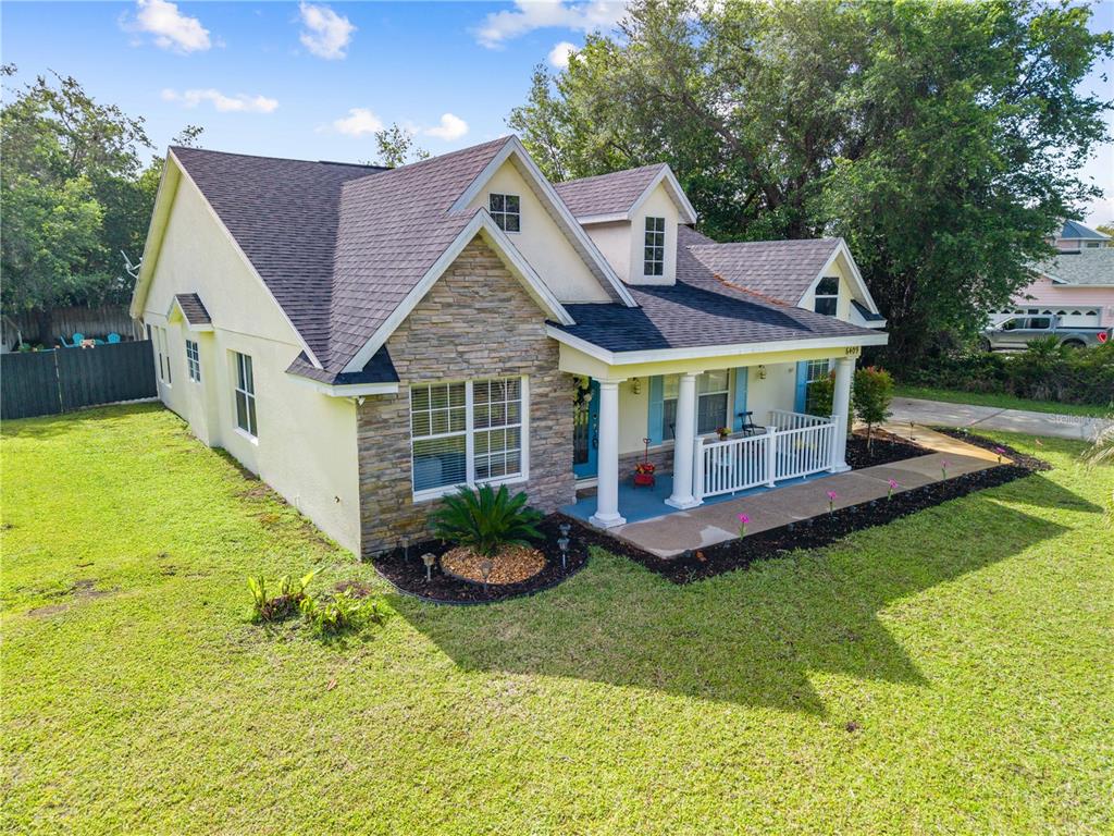 A two-story house with a stone facade, a covered front porch, and a grassy yard — 6409 SHORELINE COURT, ST CLOUD, FL