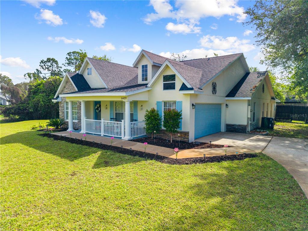 A two-story house with a front porch, blue shutters, and a garage sits on grass — 6409 SHORELINE COURT, ST CLOUD, FL