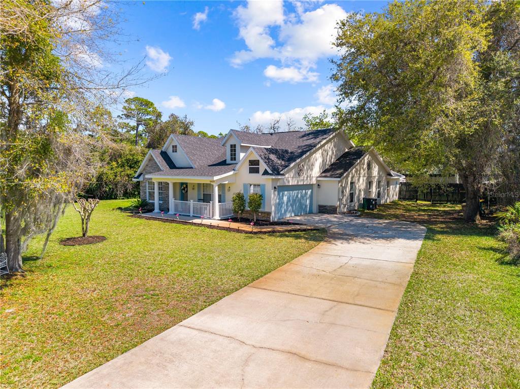A light-colored house with a front porch and a concrete driveway sits on a lawn — 6409 SHORELINE COURT, ST CLOUD, FL