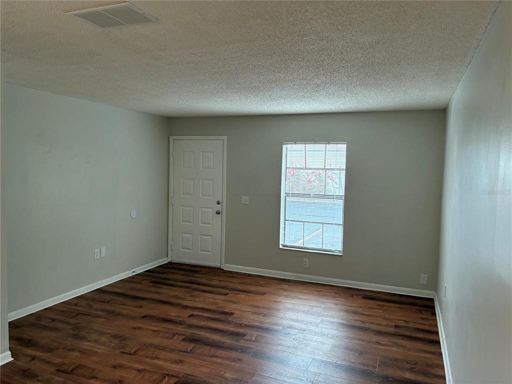 An empty room features wood-look flooring, light gray walls, a white door, and one window — 5101 S CLARICE COURT UNIT 1A, TAMPA, FL