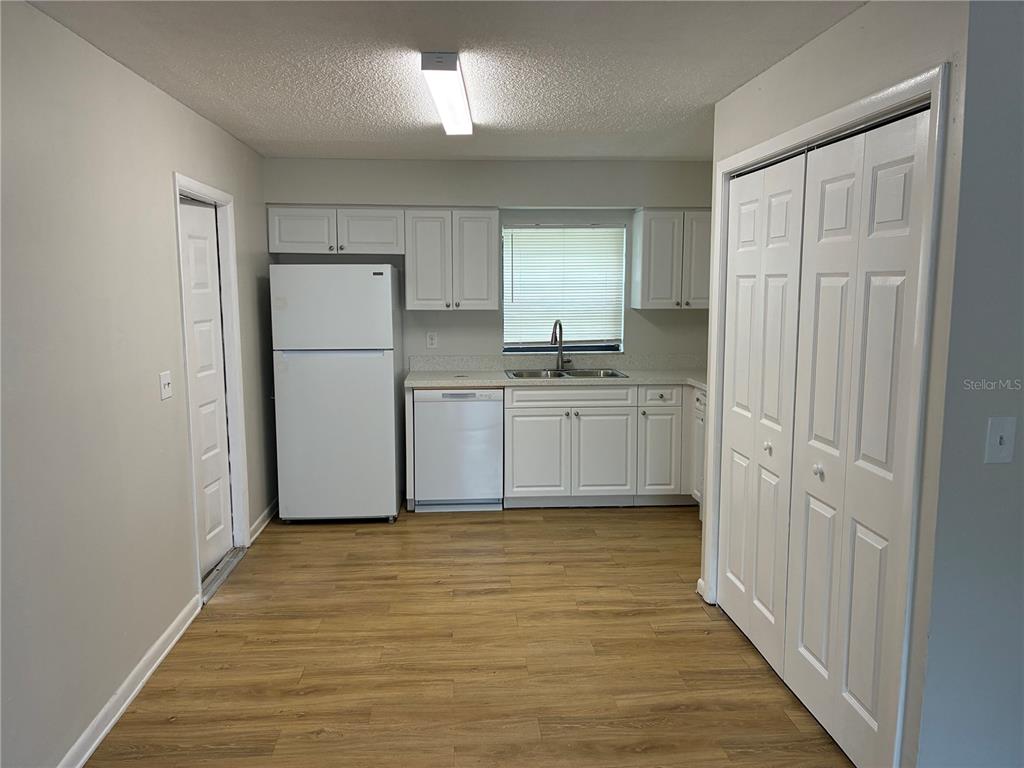 A kitchen features white cabinets, a white refrigerator, a dishwasher, and light wood-look flooring — 5101 S CLARICE COURT UNIT 1A, TAMPA, FL