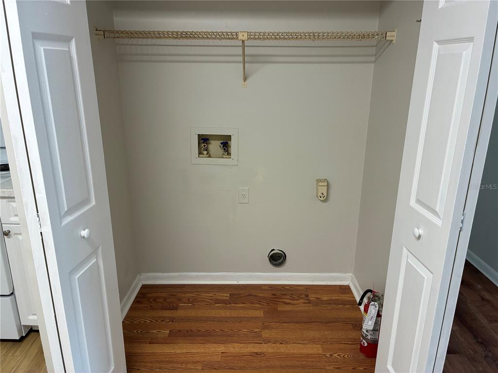 A laundry closet with wood flooring, a wire shelf, and utility hookups for a washer — 5101 S CLARICE COURT UNIT 1A, TAMPA, FL