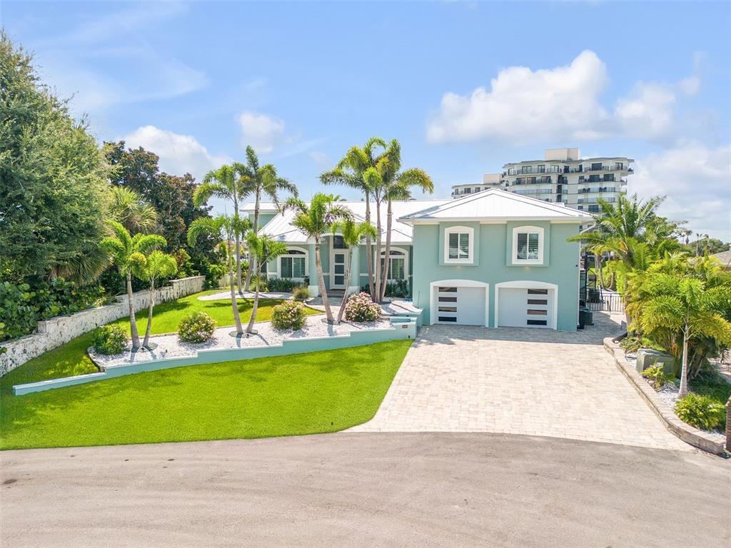 A light green house with a white roof, palm trees, and a paved driveway — 444 QUAY ASSISI COURT, NEW SMYRNA BEACH, FL