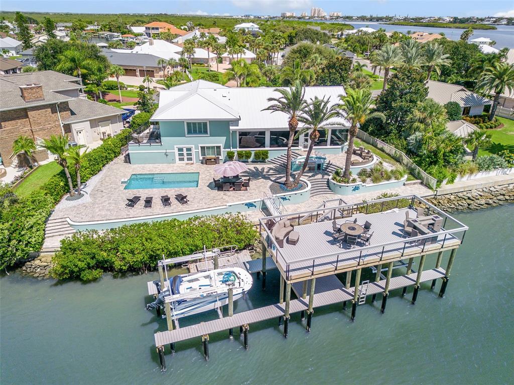 An aerial view shows a waterfront house with a pool, patio, and private boat dock — 444 QUAY ASSISI COURT, NEW SMYRNA BEACH, FL