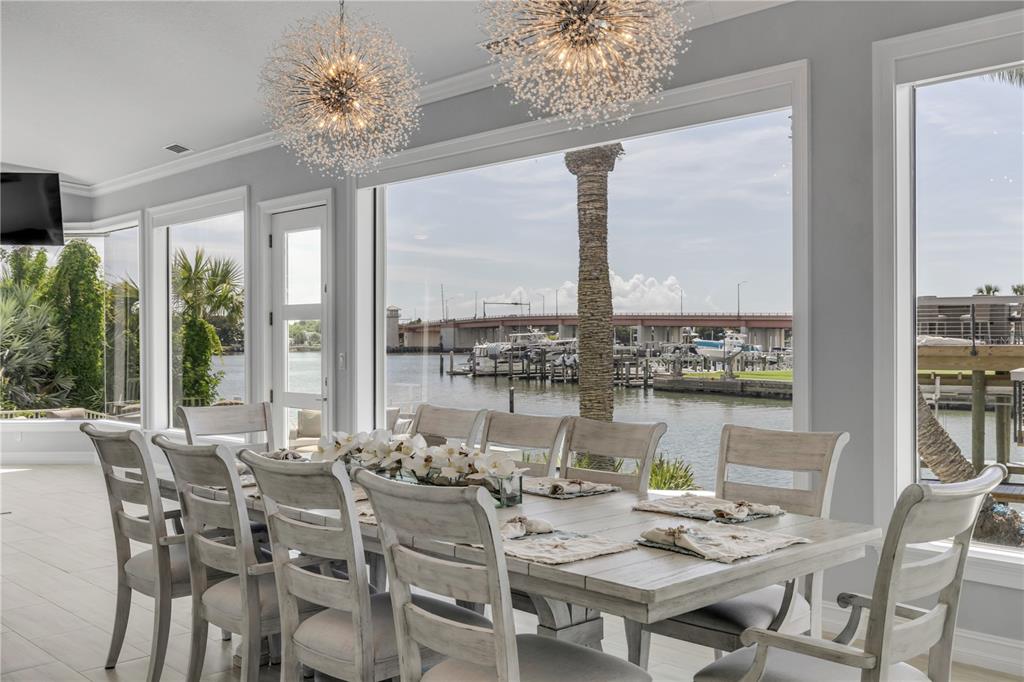 A dining room with a large table, chairs, and floor-to-ceiling windows overlooking a marina — 444 QUAY ASSISI COURT, NEW SMYRNA BEACH, FL