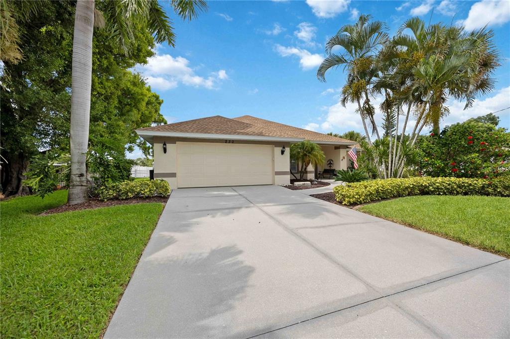 A single-story house with a beige exterior, a two-car garage, and a concrete driveway — 230 E GREEN STREET, ENGLEWOOD, FL