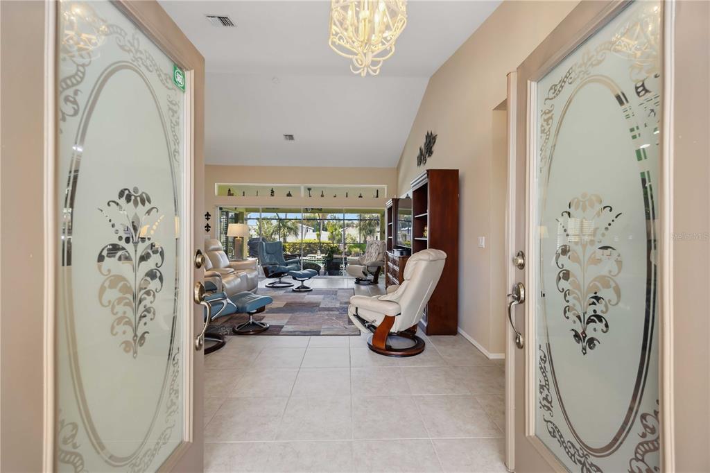 A view through double glass-paneled doors into a living room with tile floors and furniture — 230 E GREEN STREET, ENGLEWOOD, FL