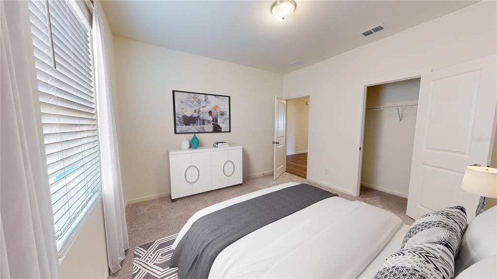 A bedroom features a bed, a white cabinet, a closet, and a doorway to another room — 14554 ITALY AVENUE, DADE CITY, FL