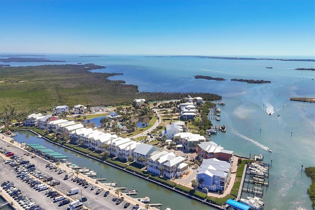 An aerial view shows a coastal residential complex with a marina and boat slips — 11727 ANGLERS CLUB DRIVE UNIT 132, PLACIDA, FL