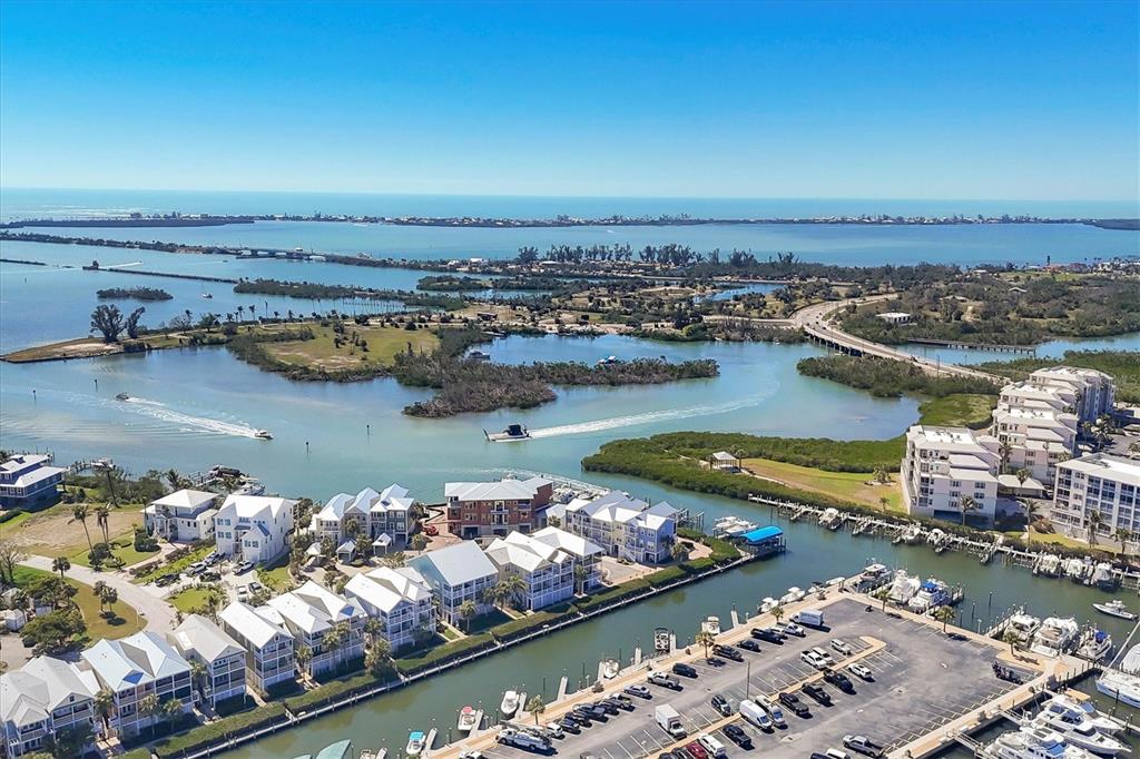 An aerial view shows waterfront townhomes, a marina, and a bridge over a coastal bay — 11727 ANGLERS CLUB DRIVE UNIT 132, PLACIDA, FL