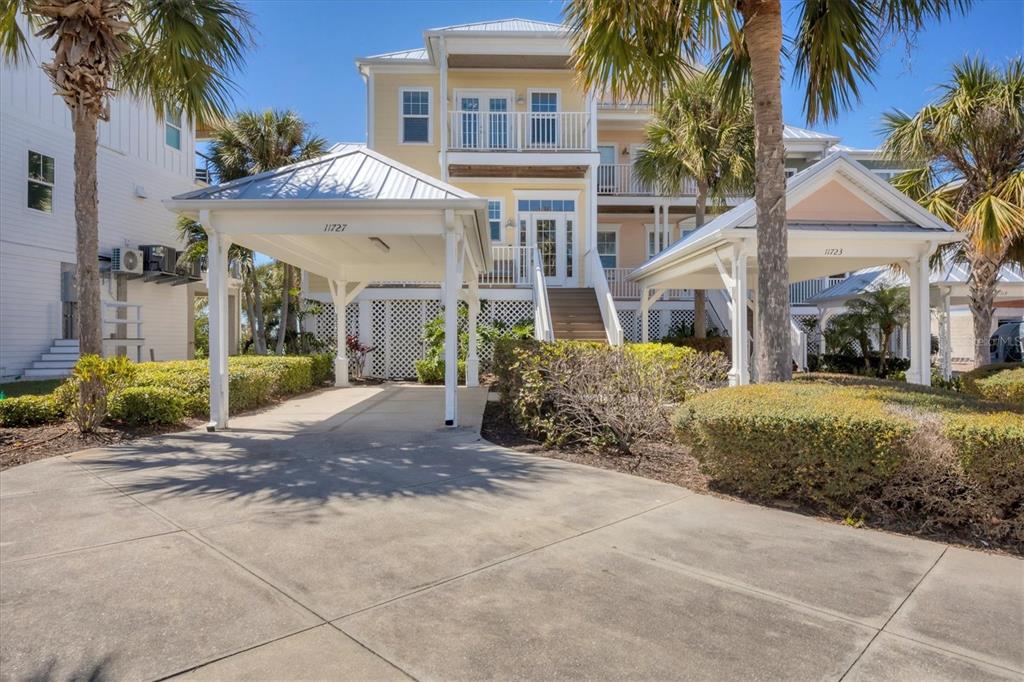 A yellow multi-story house features two separate covered carports and a central staircase — 11727 ANGLERS CLUB DRIVE UNIT 132, PLACIDA, FL