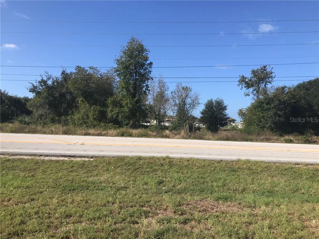 A paved road runs in front of a grassy lot with trees and power lines — CORNER OF CR 33 AND CENTENNIAL PKWY, MASCOTTE, FL
