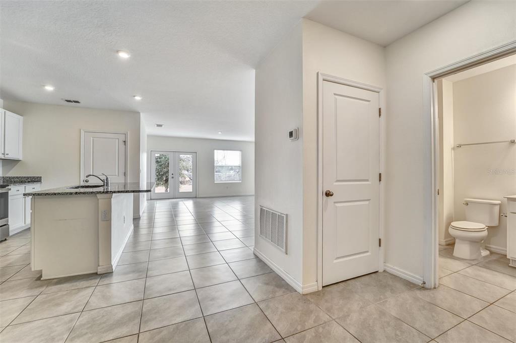 A kitchen with granite countertops and tile flooring opens into a living area and bathroom — 6978 FABEN LANE, ZEPHYRHILLS, FL