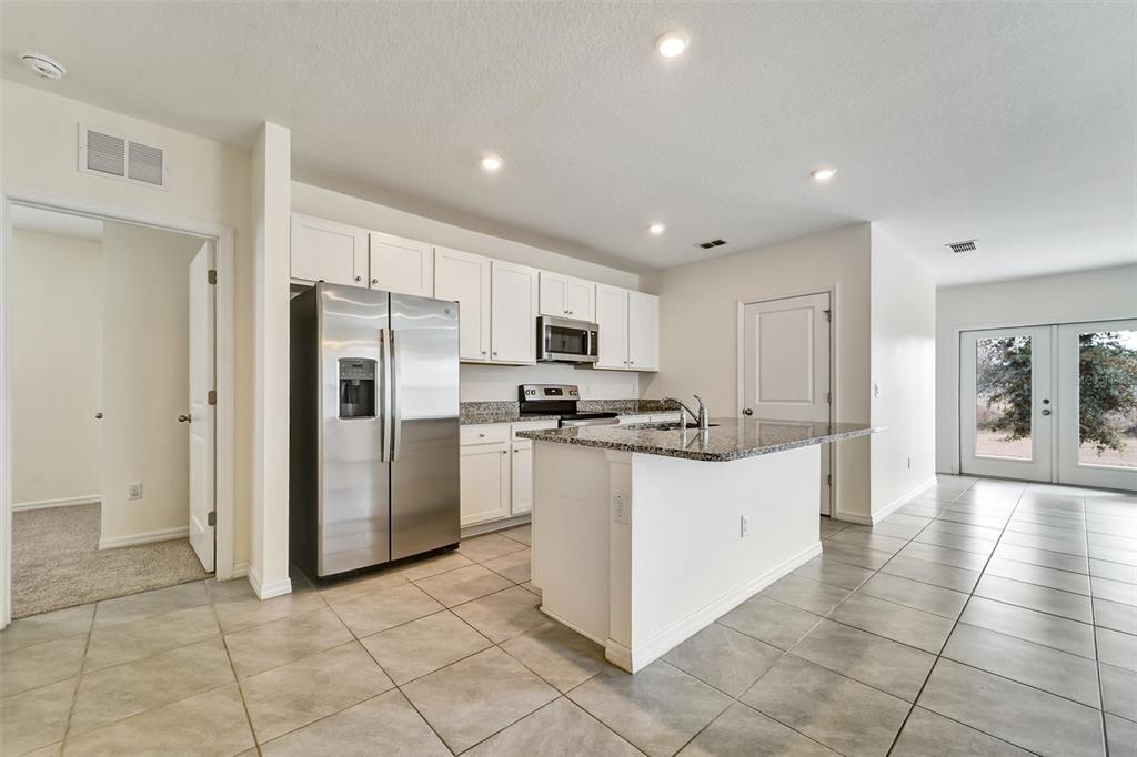 A kitchen with white cabinets, stainless steel appliances, granite countertops, and a center island — 6978 FABEN LANE, ZEPHYRHILLS, FL