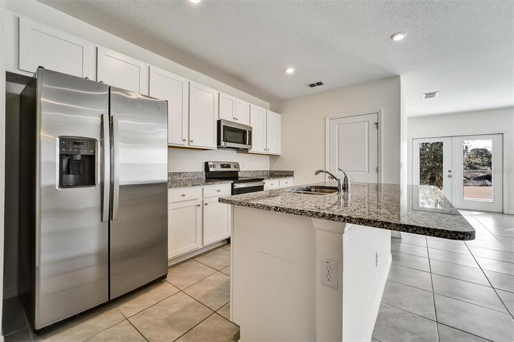 A kitchen features white cabinets, granite countertops, stainless steel appliances, and a central island — 6978 FABEN LANE, ZEPHYRHILLS, FL
