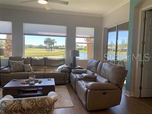 A living room features two leather sofas, a coffee table, and large windows with water views — 9712 SEA TURTLE TERRACE UNIT 102, BRADENTON, FL