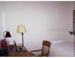 A bedroom features a desk with a laptop, a lamp, a chair, and a bed — 9712 SEA TURTLE TERRACE UNIT 102, BRADENTON, FL