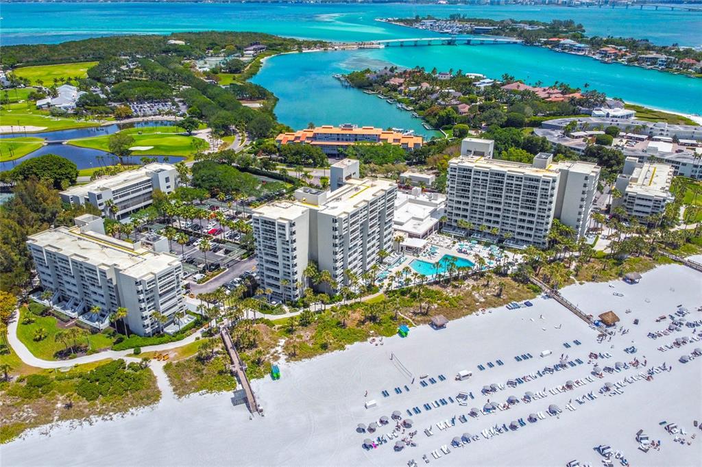 An aerial view shows beachfront high-rise condominiums, a swimming pool, and a sandy beach — 250 SANDS POINT ROAD UNIT 5106, LONGBOAT KEY, FL